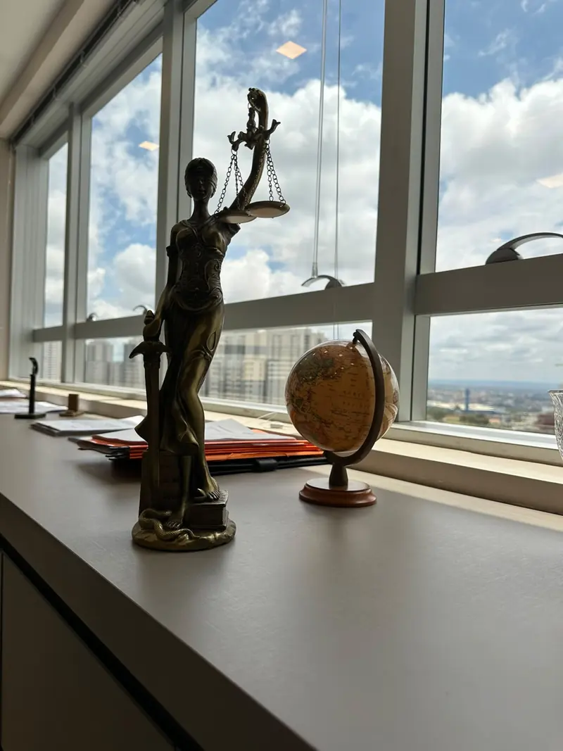 Estátua da Justiça diante da janela do escritório, com vista de Brasília